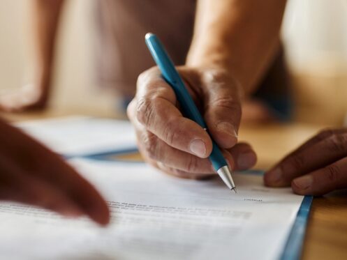 Close up of unrecognizable person signing a contract in the office.